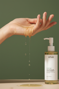 Model with golden cleansing oil dripping from her hand, Anua Heartleaf Pore Control Cleansing Oil on army green background